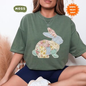 May include: A moss green t-shirt featuring a patchwork bunny design. The bunny is made of floral, gingham, and solid fabric patches. The shirt has short sleeves and a crew neck. The text "SHIPS NEXT DAY!" is in an orange starburst.
