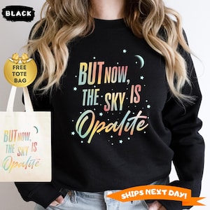 May include: Black sweatshirt with the text "BUT NOW, THE SKY IS Opalite" in colorful lettering. A matching tote bag with the same text is included. The image also includes a "SHIPS NEXT DAY!" banner.