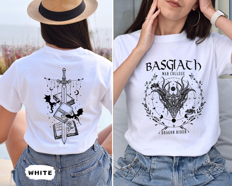 May include: White t-shirts with graphic designs. One shirt features a sword, books, bats, and celestial elements. The other shirt displays the text "BASGIATH WAR COLLEGE DRAGON RIDER" with a dragon head and floral accents.