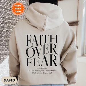 May include: A beige hoodie with the text "FAITH OVER FEAR" in black lettering. The hoodie also includes the text "PSALMS 118:6" and a quote from the Bible verse: "The Lord is on my side; I will not fear. What can man do unto me?"