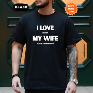 May include: Black t-shirt with the text "I LOVE IT WHEN MY WIFE LETS ME PLAY RUNESCAPE" in white. The shirt also has a "SHIPS NEXT DAY!" sticker and a "BLACK" label.