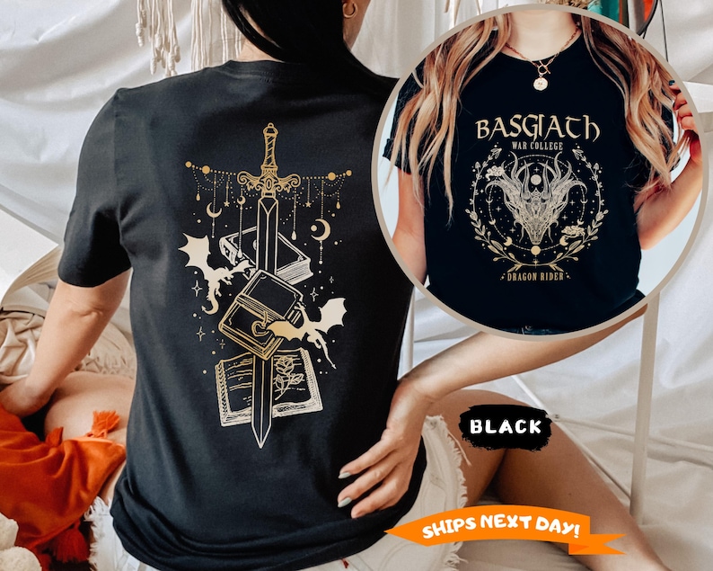 May include: Black t-shirt with a gold graphic of a sword, books, and bats. The shirt also features the text "BASGIATH WAR COLLEGE DRAGON RIDER" in a circular design. The shirt is a crew neck and short-sleeved.