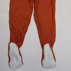 May include: A pair of rust-colored baby leggings with white footie feet.