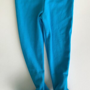May include: A pair of bright blue leggings with white feet. The leggings are made of a soft, stretchy fabric.