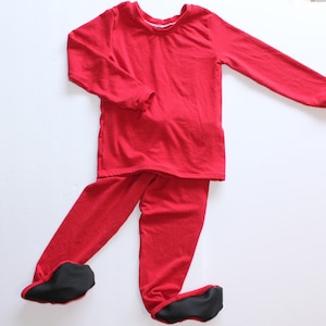 May include: A solid red long-sleeve shirt and matching footed pants set. The shirt features a crew neckline and long sleeves. The pants have integrated foot coverings with black textured soles on the bottom of each foot for added grip.