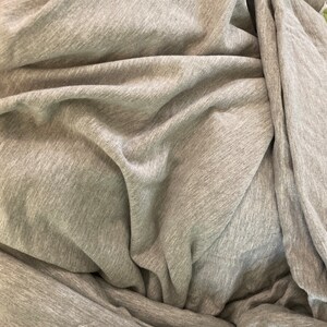 May include: A close-up of a gray, textured fabric with a soft, wrinkled appearance.