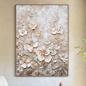 May include: A large rectangular wall art piece featuring a textured, three-dimensional floral composition in shades of cream, beige, and white. The painting displays layered petals and botanical elements with visible brushstrokes and impasto techniques.