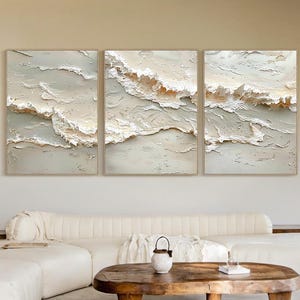 May include: A triptych wall art set featuring three rectangular canvases with heavy impasto texture in shades of cream, beige, and soft sage green. The artwork depicts abstract, layered wave-like forms with raised paint strokes creating depth.