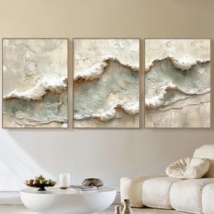 May include: A triptych wall art set featuring three rectangular canvases with heavy impasto texture. The paintings depict abstract ocean waves in shades of cream, beige, and soft sage green, with thick, raised white paint creating a cresting effect.