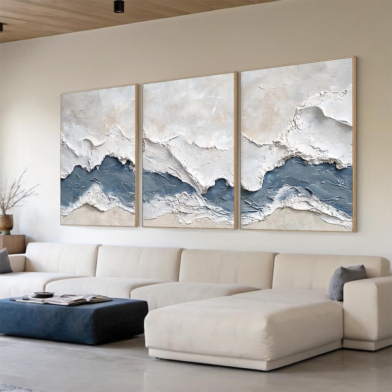 May include: A triptych wall art set featuring three rectangular canvases with heavy impasto texture. The paintings display abstract horizontal layers of white, cream, and muted blue paint, creating a raised, rugged landscape effect across all panels.