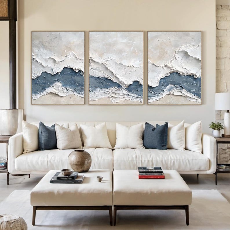 May include: A triptych of textured abstract paintings featuring layered white, cream, and slate blue impasto paint. The artwork displays horizontal, wave-like ridges and deep grooves, creating a three-dimensional effect across three rectangular canvases.