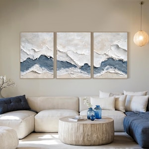 May include: A triptych wall art set featuring three rectangular canvases with heavy impasto texture. The artwork displays abstract horizontal layers of white, cream, and muted blue paint, creating a raised, sculptural effect across all panels.