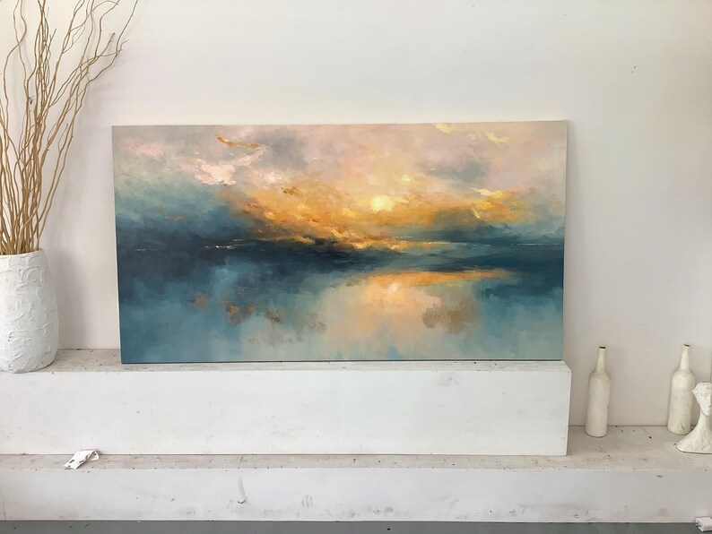 Peut inclure: Une peinture de paysage rectangulaire pr&eacute;sentant un m&eacute;lange de tons bleu sarcelle profond, bleu doux et jaune dor&eacute; chaud. L'&oelig;uvre repr&eacute;sente un horizon atmosph&eacute;rique et brumeux avec une lumi&egrave;re se refl&eacute;tant sur une surface calme.