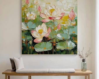 May include: A square oil painting featuring a close-up of lotus flowers in a pond. The flowers are white and pink with yellow centers, surrounded by green lily pads. The artwork is framed in gold and hangs above a wooden bench.