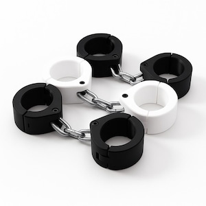 Op de afbeelding: Een set van zes zwarte en witte handboeien verbonden door zilveren kettingen. De handboeien zijn cirkelvormig met een scharnierende opening en een vergrendelingsmechanisme. De foto is gemaakt tegen een witte achtergrond.