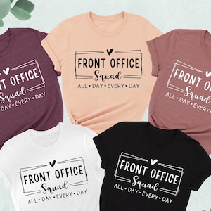 May include: Five t-shirts in different colors with the text "Front Office Squad All Day Every Day" printed on them. The shirts are laid out on a white surface with a cup of coffee and a pair of shoes.