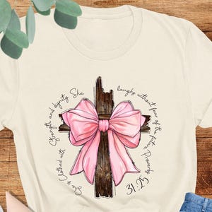 Proverbs She is Clothed with Strength Shirt, Cross Coquette Bow Shirt, Christian Women&#39;s Gift, Bible Verse Shirt, Religious Shirt, Pink Bow