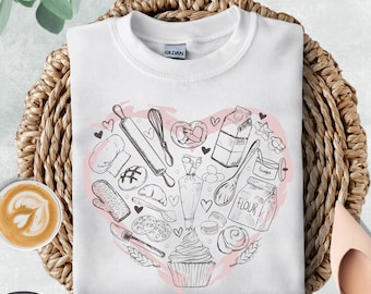 May include: White sweatshirt with a heart-shaped design featuring baking tools and ingredients in a line drawing style. The design includes a rolling pin, whisk, and a cupcake. The word "WHITE" is printed on the top right.