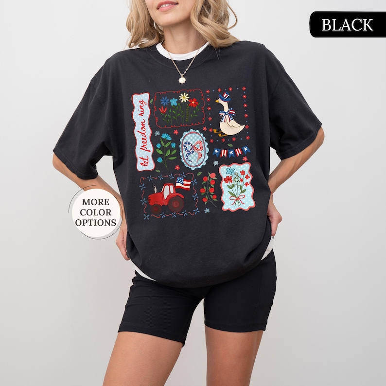May include: Black short-sleeved t-shirt with a white crew neck. The shirt features a patchwork design with patriotic motifs, including flowers, a tractor, a goose, and the text "let freedom ring."