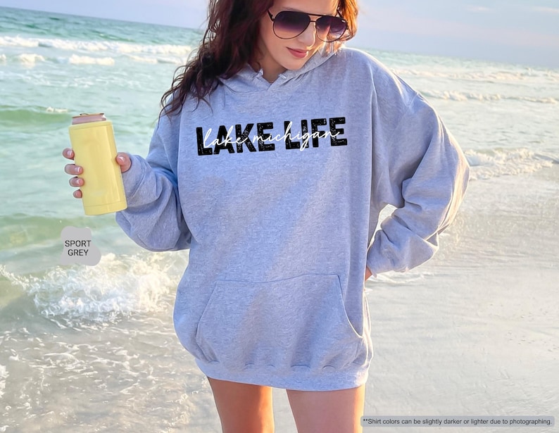 Peut inclure: Un sweat-shirt &agrave; capuche gris sport avec le texte noir LAKE LIFE et le texte cursif blanc lake michigan imprim&eacute; sur le devant. Le v&ecirc;tement comprend une poche kangourou frontale, des manches longues et une capuche avec cordons assortis.