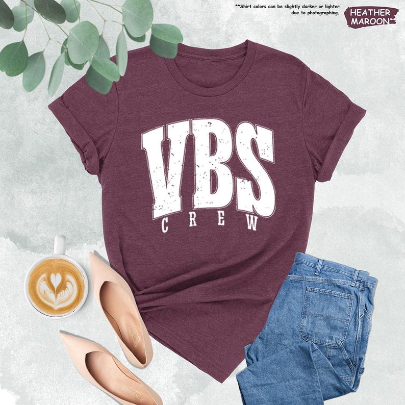 a women's vbs crew t - shirt next to a cup of coffee