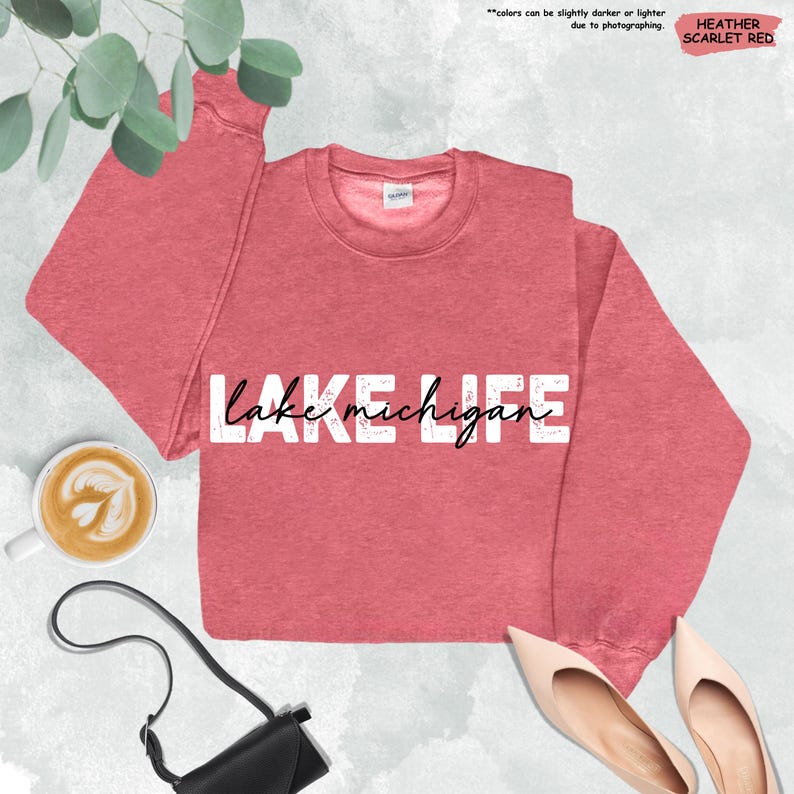 Peut inclure: Un sweat-shirt &agrave; col rond rouge &eacute;carlate chin&eacute; avec le texte LAKE en lettres capitales blanches et le texte michigan en &eacute;criture cursive noire au centre. Le v&ecirc;tement poss&egrave;de des manches longues et un col c&ocirc;tel&eacute; avec une &eacute;tiquette visible.