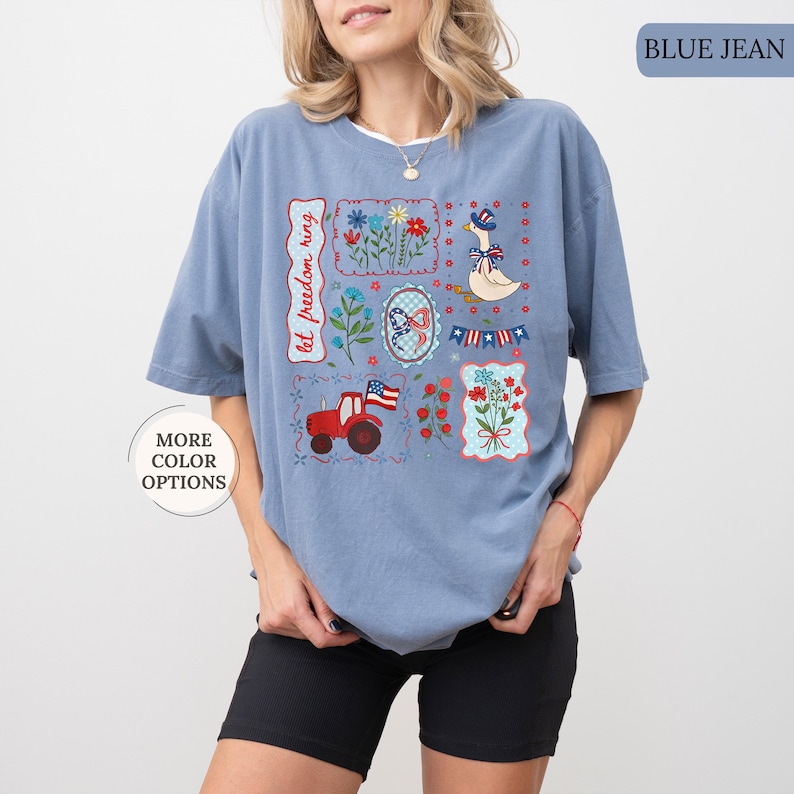 May include: Blue jean colored t-shirt with a white collar. The shirt features several embroidered patches with patriotic themes, including a tractor, flowers, a goose in a hat, and the text "let freedom ring."