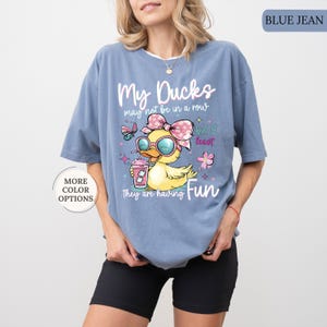 May include: Blue jean colored t-shirt with the text "My Ducks may not be in a row but at least they are having Fun." The shirt features a cartoon duck wearing sunglasses and a bow, holding a drink.