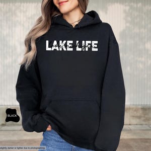 Peut inclure: Un sweat-shirt &agrave; capuche noir avec le texte blanc vieilli LAKE LIFE et le texte cursif noir plus petit Lake Michigan superpos&eacute;. Le v&ecirc;tement comprend une poche kangourou &agrave; l'avant, des manches longues et une capuche avec des cordons assortis.
