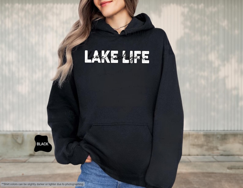 Peut inclure: Un sweat-shirt &agrave; capuche noir avec le texte blanc vieilli LAKE LIFE et le texte cursif noir plus petit Lake Michigan superpos&eacute;. Le v&ecirc;tement comprend une poche kangourou &agrave; l'avant, des manches longues et une capuche avec des cordons assortis.