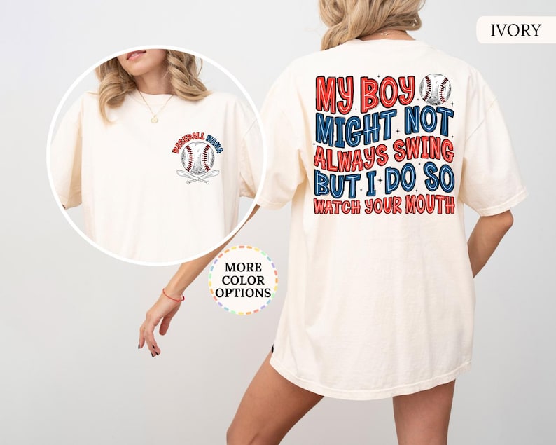 May include: Ivory-colored t-shirt with baseball-themed graphics. The front features a baseball and crossed bats with the text "Baseball Mom". The back displays the text "My boy might not always swing but I do so watch your mouth" in red and blue.