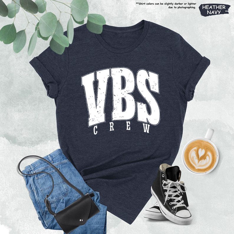 a women's vbs crew t - shirt next to a cup of coffee