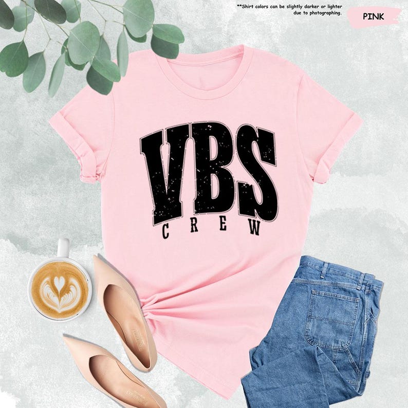 a pink vbs crew shirt next to a cup of coffee