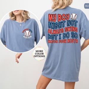 May include: A blue jean colored t-shirt with the text "MY BOY MIGHT NOT ALWAYS SWING BUT I DO SO WATCH YOUR MOUTH" in red, white, and blue. A baseball graphic is on the back and front of the shirt. The shirt has short sleeves.
