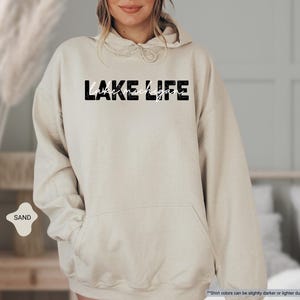 Peut inclure: Un sweat &agrave; capuche couleur sable arborant le texte LAKE LIFE dans une police noire &eacute;paisse et vieillie, avec les mots lake michigan inscrits en fine &eacute;criture cursive blanche au centre de la poitrine et une poche kangourou sur le devant.