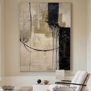 May include: A large rectangular canvas painting featuring abstract layers of beige, tan, and cream tones with bold black vertical brushstrokes and thin, sweeping black lines. The artwork is displayed in a frame and includes the text ArtfuCanvas.