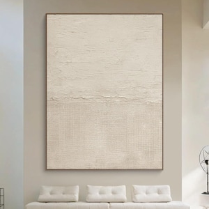 May include: A large rectangular wall art piece featuring a two-tone beige composition. The top half displays a thick, textured impasto paint application, while the bottom half consists of a fine, uniform grid pattern in a matching light beige hue.