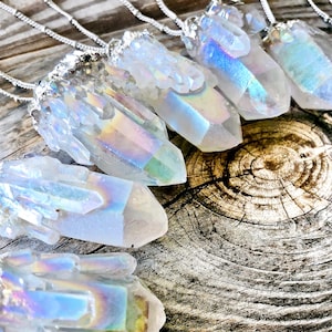 Peut inclure: Un ensemble de pendentifs en cristal iridescent sur des chaînes en argent. Les cristaux sont clairs avec un reflet arc-en-ciel et sont disposés sur une surface en bois.