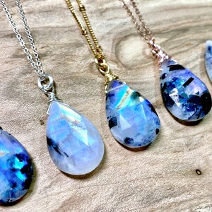 Puede incluir: Cinco collares de plata, oro y oro rosa con colgantes de l&aacute;grima de piedra de luna arco&iacute;ris iridiscente. Los colgantes son facetados y tienen un color azul y blanco.