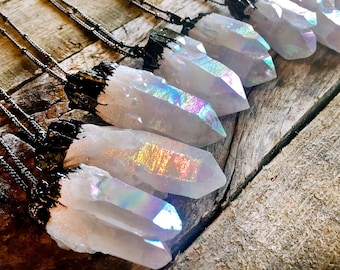 May include: A collection of iridescent crystal point necklaces with black cord. The crystals are white with rainbow flashes of color.