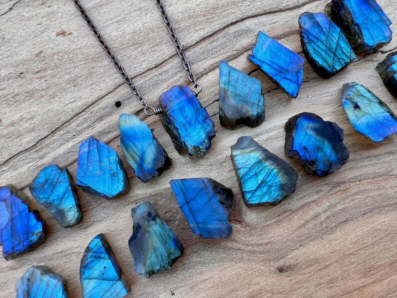 a collection of blue and black gemstones, including various types of stones, arranged on a wooden surface.