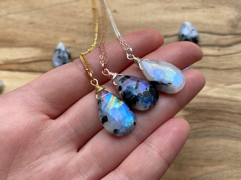 Puede incluir: Tres collares de plata, oro y oro rosa con colgantes de piedra de luna arco&iacute;ris en forma de l&aacute;grima.