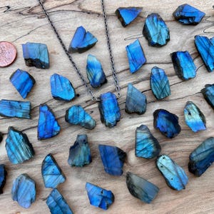 a collection of blue and black crystals or gemstones arranged on a wooden surface, with a copper coin placed among them.