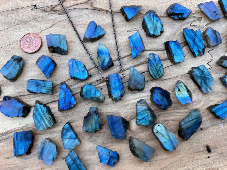 a collection of blue and black crystals or gemstones arranged on a wooden surface, with a copper coin placed among them.