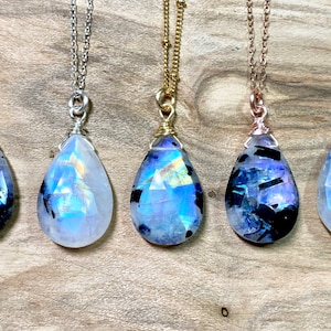 Puede incluir: Cinco colgantes de piedra lunar arco&iacute;ris en forma de l&aacute;grima en cadenas de plata, oro y oro rosa. Los colgantes son facetados y tienen un brillo iridiscente.