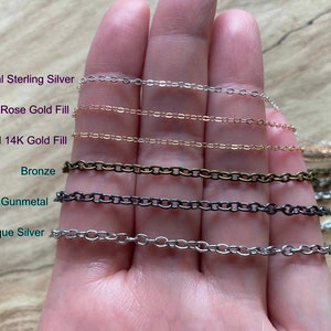 May include: A close-up of a hand holding six different chain styles. The chains are labeled "Real Sterling Silver", "Real 14K Rose Gold Fill", "Real 14K Gold Fill", "Bronze", "Gunmetal", and "Antique Silver".