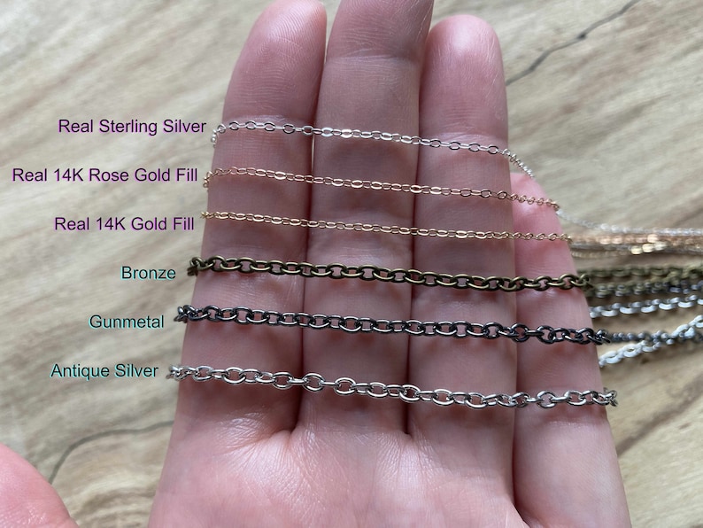 May include: A close-up of a hand holding six different chain styles. The chains are labeled "Real Sterling Silver", "Real 14K Rose Gold Fill", "Real 14K Gold Fill", "Bronze", "Gunmetal", and "Antique Silver".