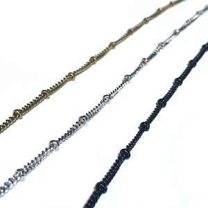 Peut inclure: Trois cha&icirc;nes avec des perles de diff&eacute;rentes couleurs. Les cha&icirc;nes sont argent&eacute;es, noires et dor&eacute;es.