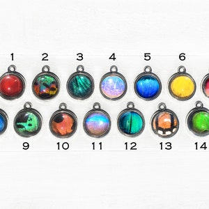 May include: Assortment of 14 round pendants featuring colourful butterfly wings encased in silver settings. The pendants are numbered 1 through 14.