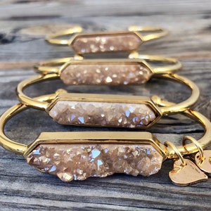 May include: Four gold bracelets with a light brown crystal charm. Each bracelet has a heart charm and a letter charm.
